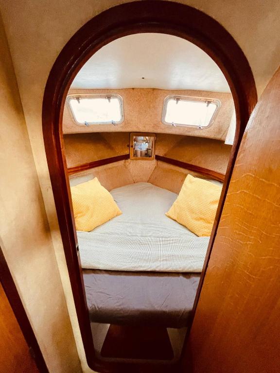 Cama pequeña en habitación pequeña con 2 ventanas en Stylish 80´s Fishing Boat, en Barcelona