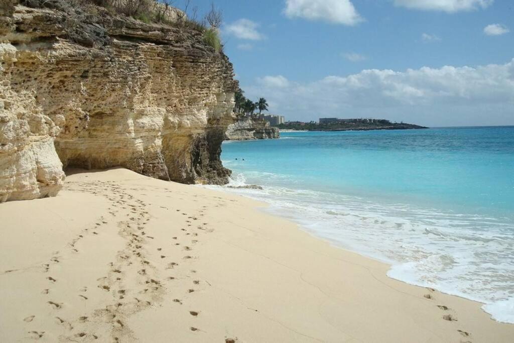 a beach with footprints in the sand next to the water at Fun under the sun! in Cupecoy