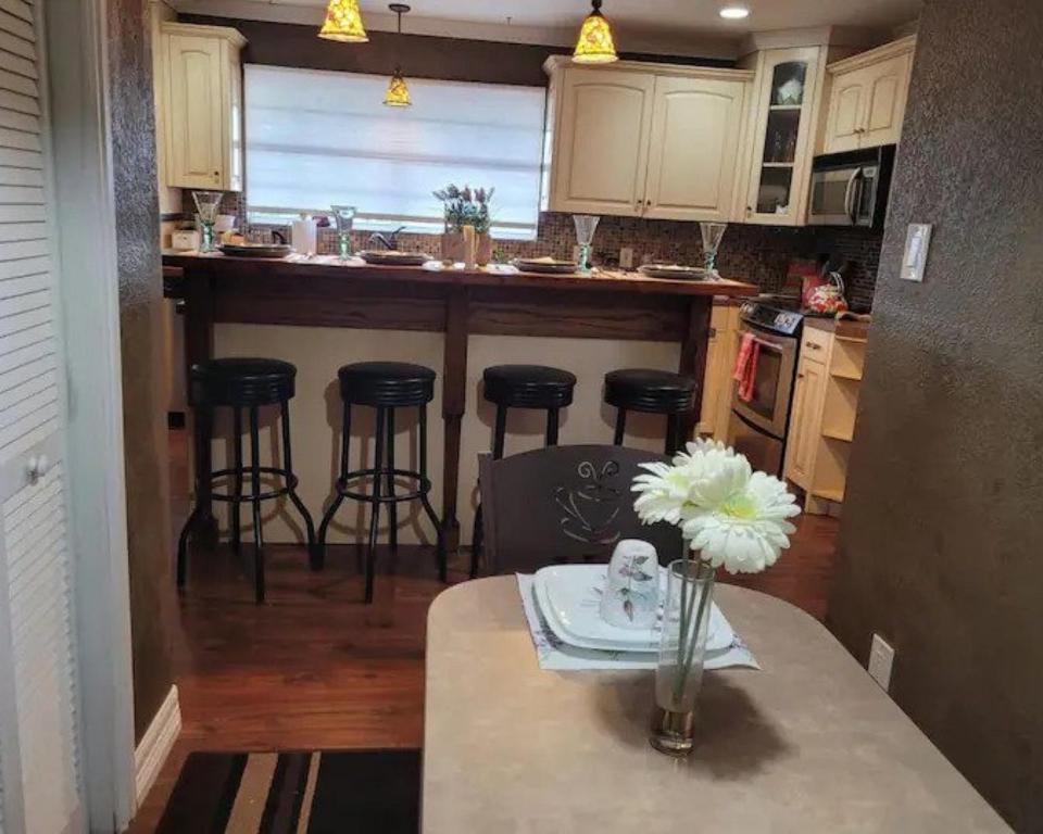 a kitchen with a table and bar with stools at Entire 2br 2ba hilltop view home Sleeps 8 pets 4 acres Jacuzzi Central AC Kingbeds Free Wifi-Parking Kitchen WasherDryer Starry Terrace Two Sunset Dining Patios Grill Stovetop Oven Fridge OnsiteWoodedHiking Wildlife CoveredPatio4pets & Birds Singing! in Marble Falls