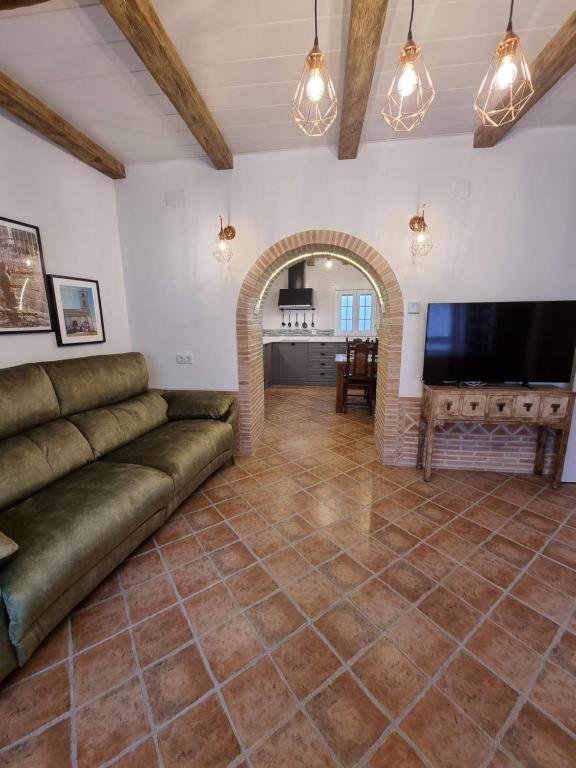 een woonkamer met een bank en een televisie bij Casa Flora - Casa rural con encanto in El Carpio de Tajo