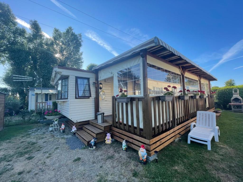 uma pequena casa com um alpendre e uma cadeira branca em Mobilhome em Noyelles-sur-Mer