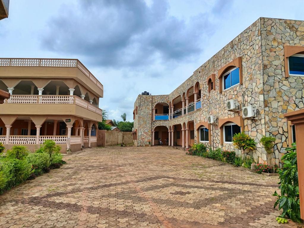 an exterior view of a large stone building with a courtyard at Bois vert Hôtel in Abomey
