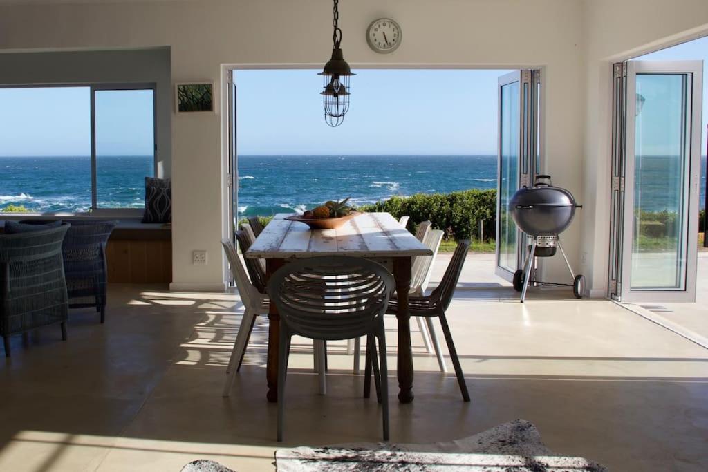 a dining room with a table and a view of the ocean at Seafront house with a view in Kleinmond