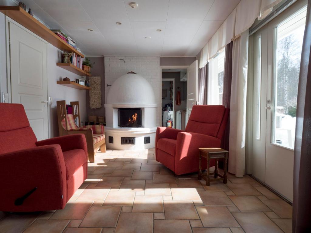 a living room with red chairs and a fireplace at Moonlight House Large holiday villa with sauna and free parking in Rovaniemi