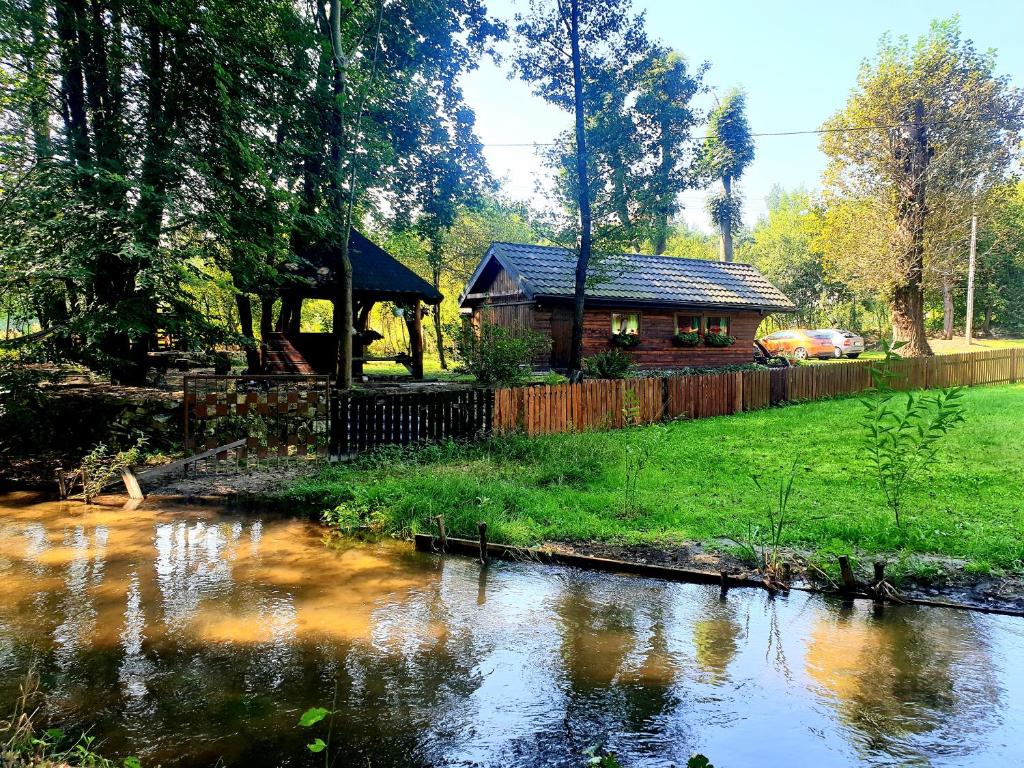 uma cabana de madeira junto a um rio com uma casa em Jurajska Sielanka - domek nad rzeczką em Pradła