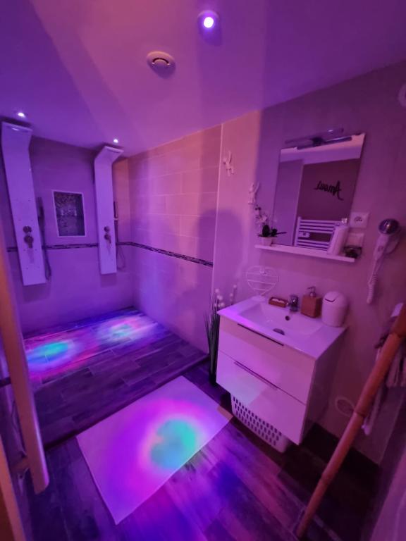 a purple bathroom with a sink and a mirror at Chambres d&#39;hôtes avec jacuzzi privatif in Westrehem