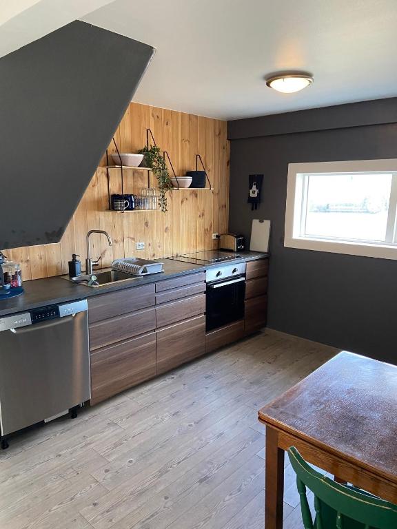a kitchen with wooden cabinets and a sink and a table at The Little Guesthouse Downtown - Keflavik Airport in Keflavík