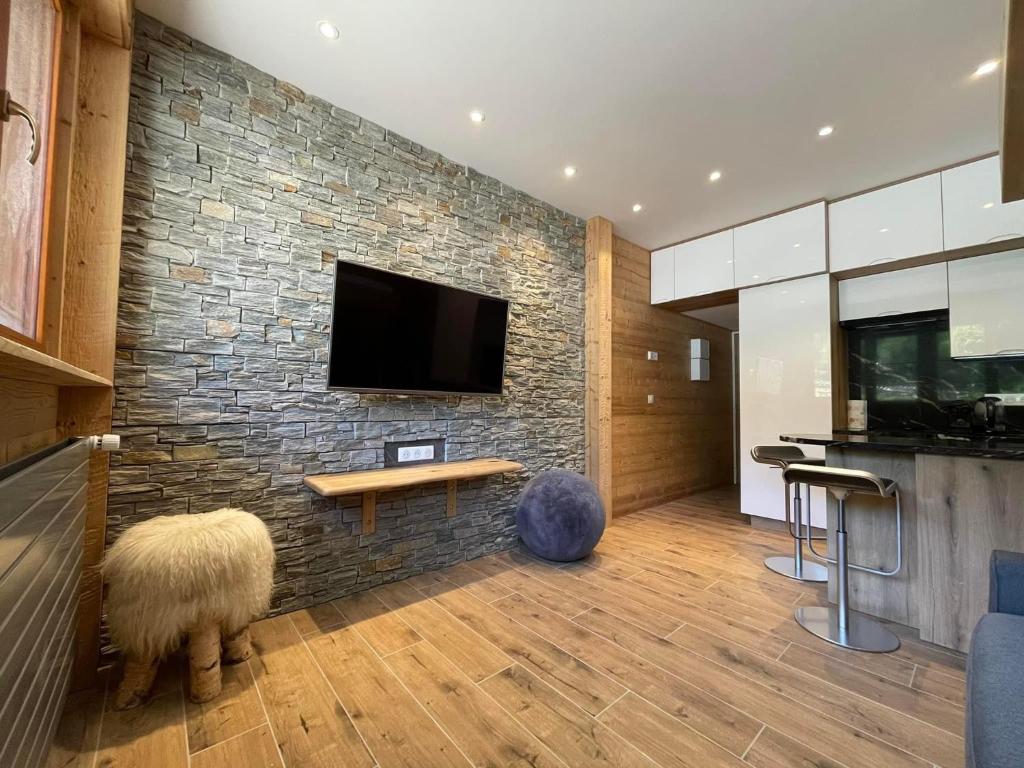 a living room with a tv on a stone wall at Rendez-vous au studio in Valloire