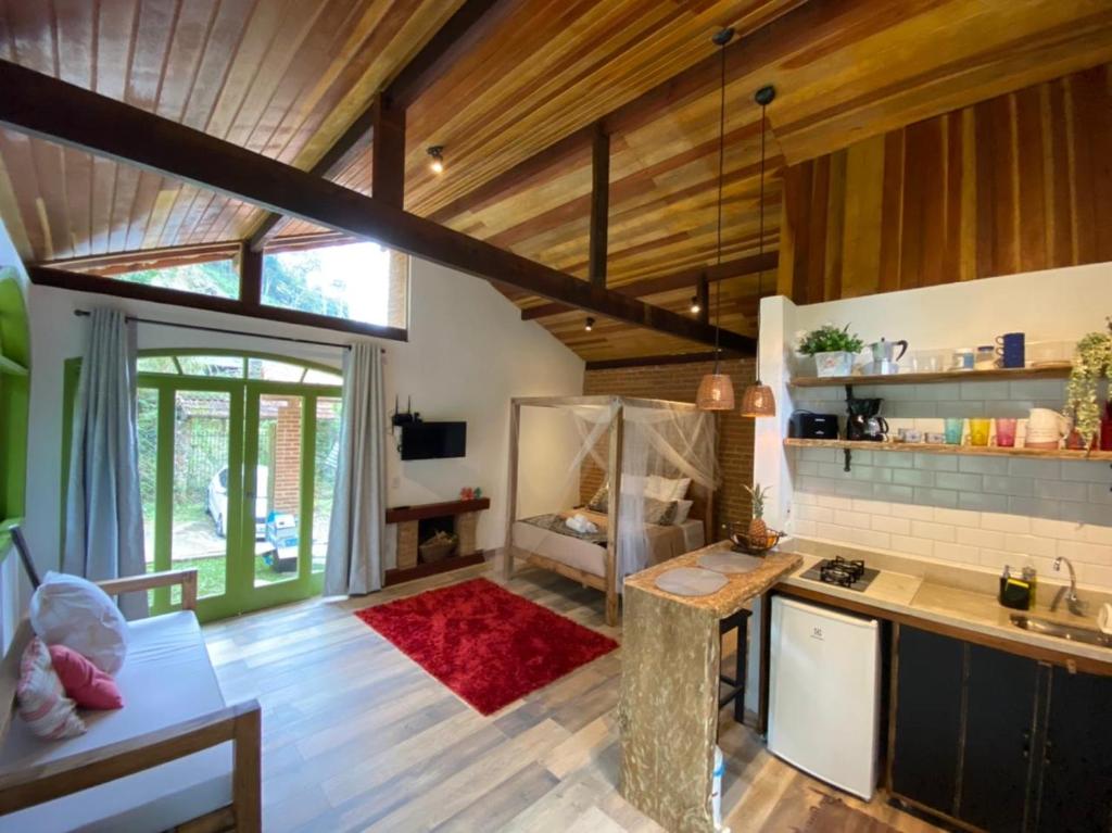 a kitchen with wooden ceilings and a living room at Loft Fazenda Inglesa in Petrópolis