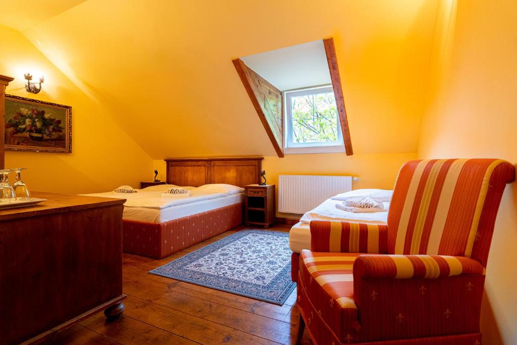 een slaapkamer met 2 bedden, een stoel en een raam bij Penzión Cosmopolitan I. in Banská Štiavnica