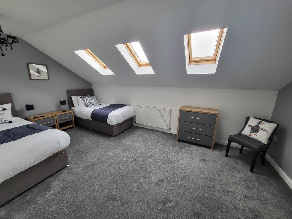 a attic bedroom with two beds and skylights at Immaculate 7 Bed House in Ashton-under-Lyne OL7 in Manchester