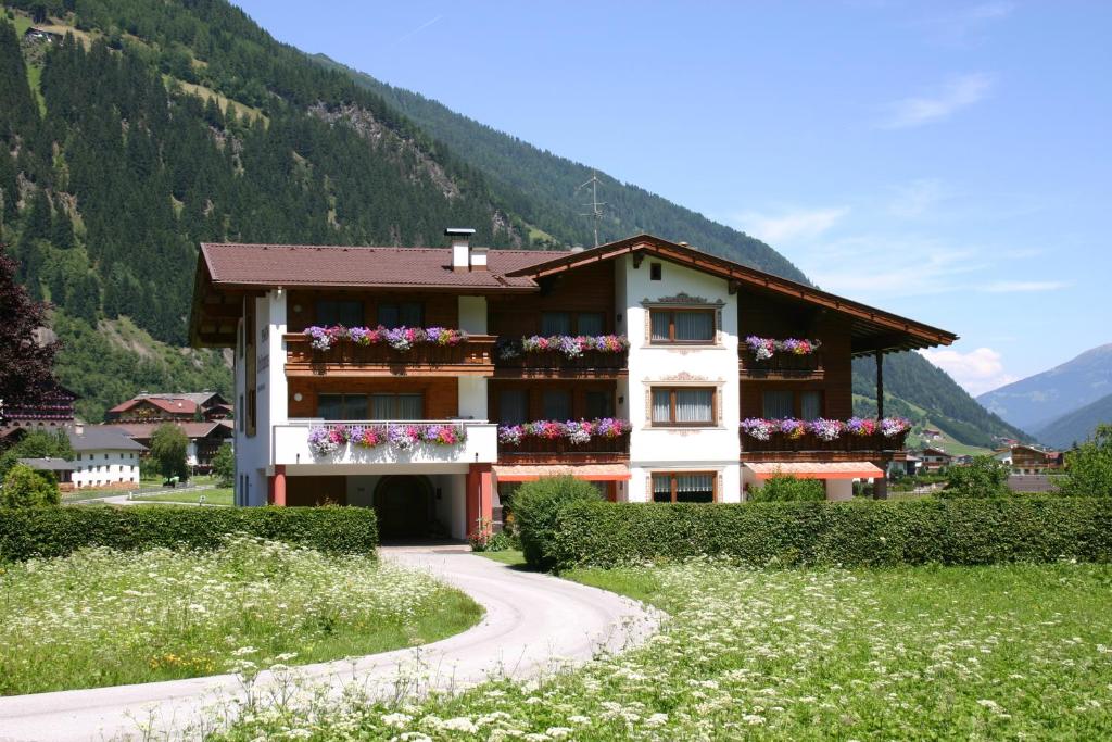 a building with flowers on the windows and a winding road at Pension Christophorus in Neustift im Stubaital