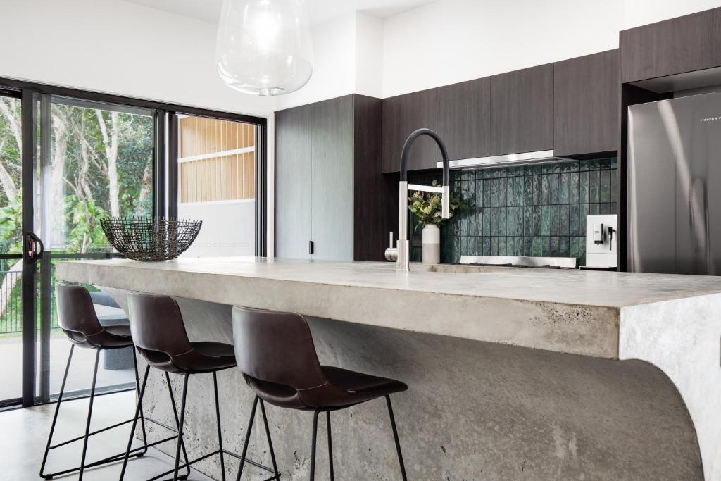 a kitchen with a large marble counter and stools at Luxury Modern 4 BR Pet Friendly Family Beach Home in Yaroomba