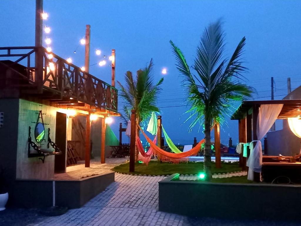 a playground with a hammock and palm trees at night at Pousada Mar e Paz in São Francisco do Sul