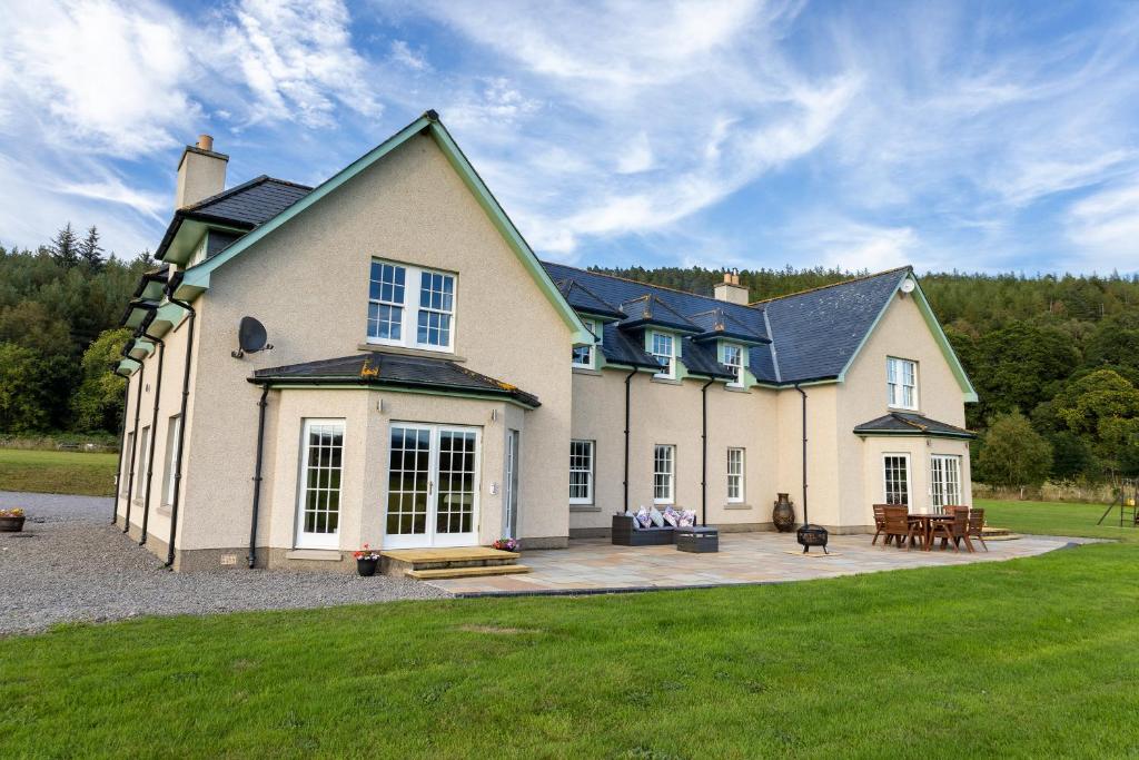 a large house with a patio in the yard at Beallach Lodge in Culrain
