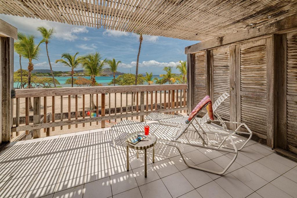 Un balcón con una silla, una mesa y el océano en Sapphire Beach Beachfront Condo Free Wi - Fi! - Save! en East End