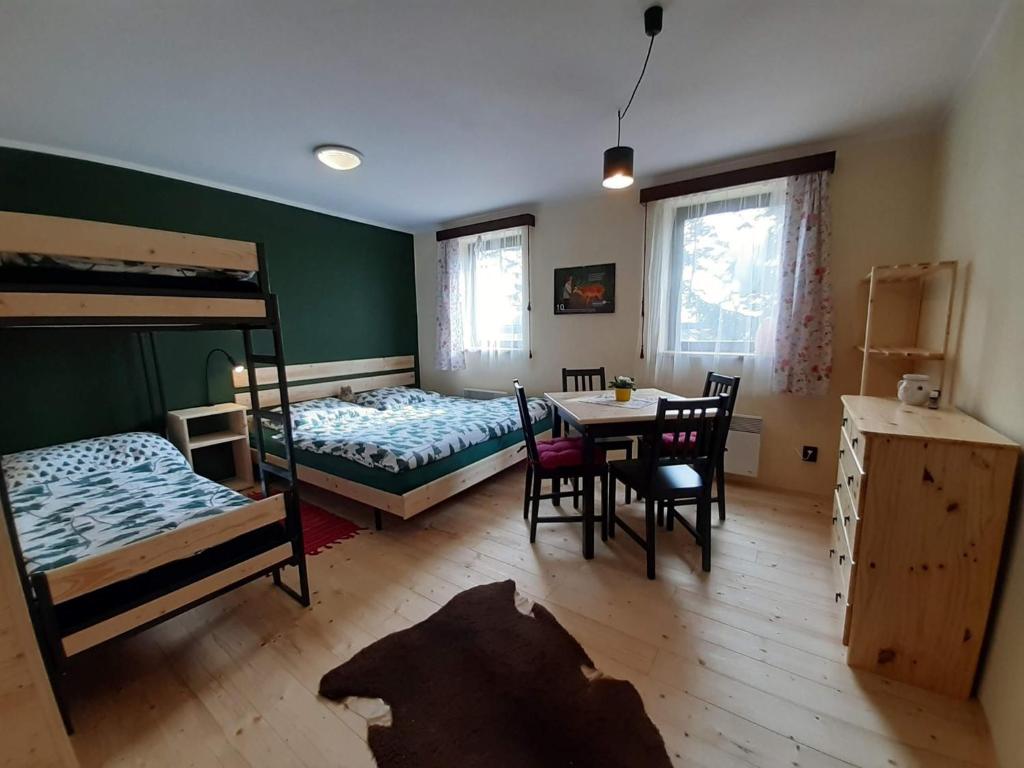 a room with two bunk beds and a table and chairs at Chata Nad rybníkem Hnačov 