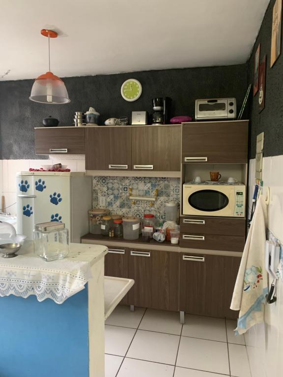 Il comprend une cuisine avec des placards bruns et du carrelage blanc. dans l'établissement Residencial bela vista, à Betim
