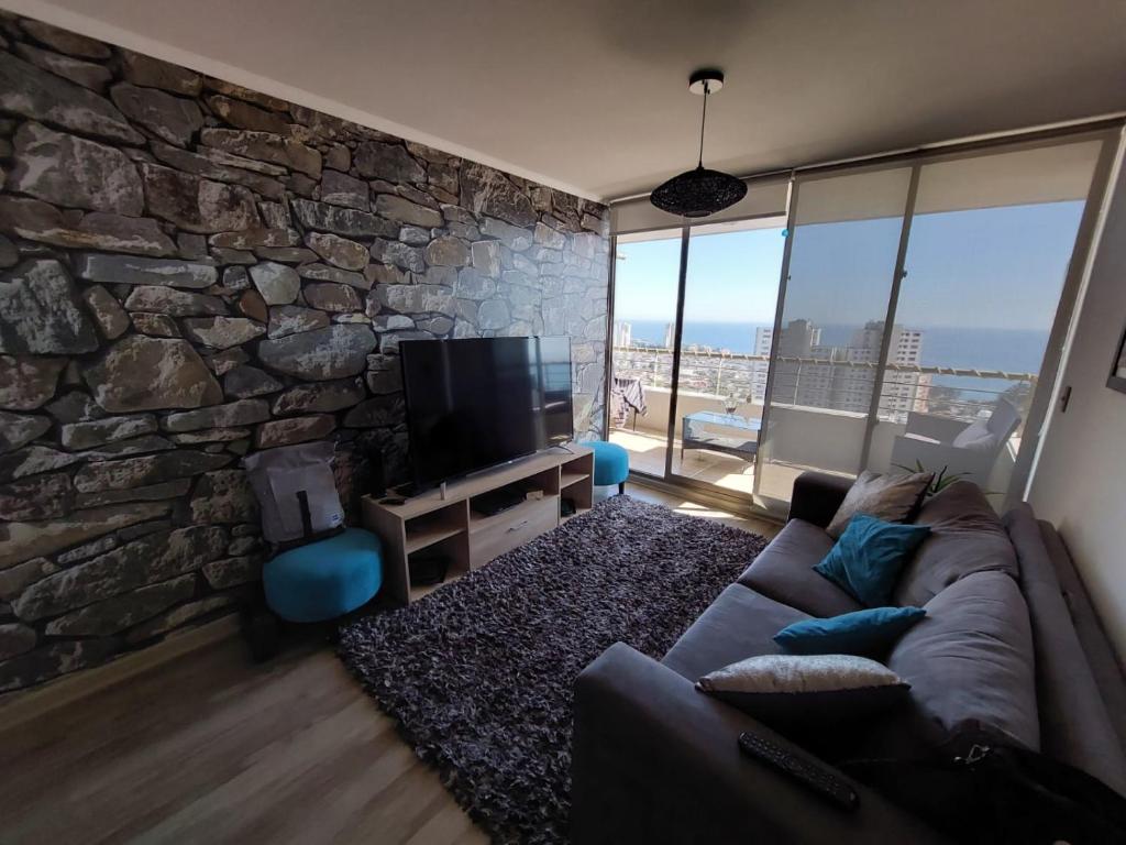 a living room with a couch and a stone wall at Departamento Concón Vista Montemar II in Concón