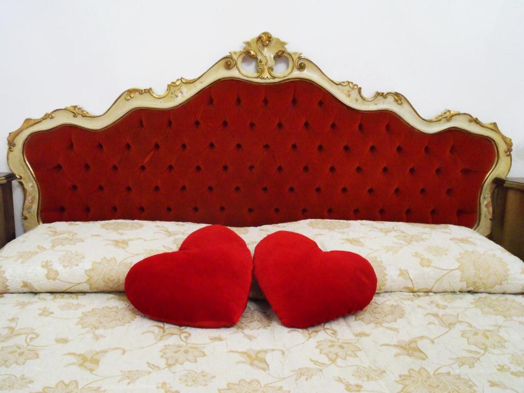 dos corazones rojos sentados en la parte superior de una cama en Art&Coffee, en Verona