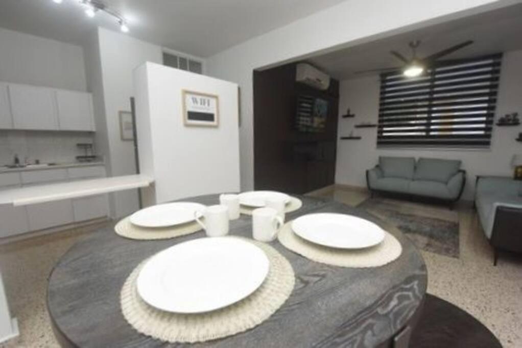 a table in a living room with white plates on it at Cozy apartment in the heart of the city in Ponce