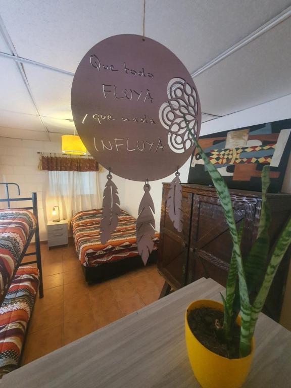 una habitación con una mesa con una planta y un cartel en Hostel Morada Roots en Córdoba