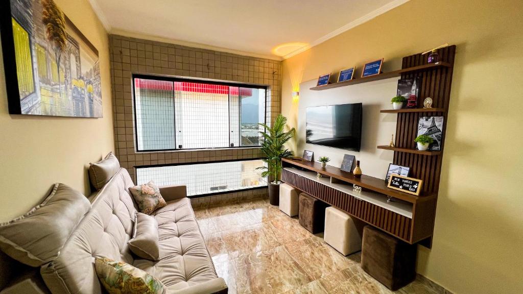 a living room with a couch and a television at Frente para o Mar com Vista Incrível - Porto1003 in Praia Grande