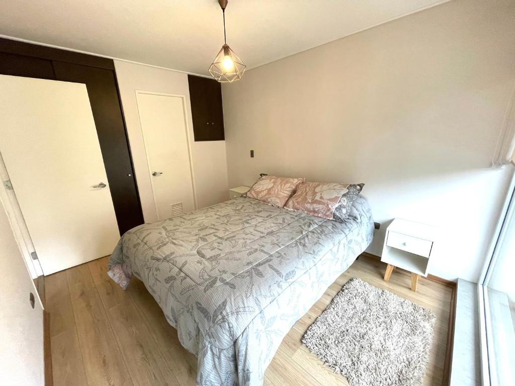 a small bedroom with a bed and a rug at Apartamento en exclusivo barrio Lomas de san Andrés con estacionamiento in Concepción