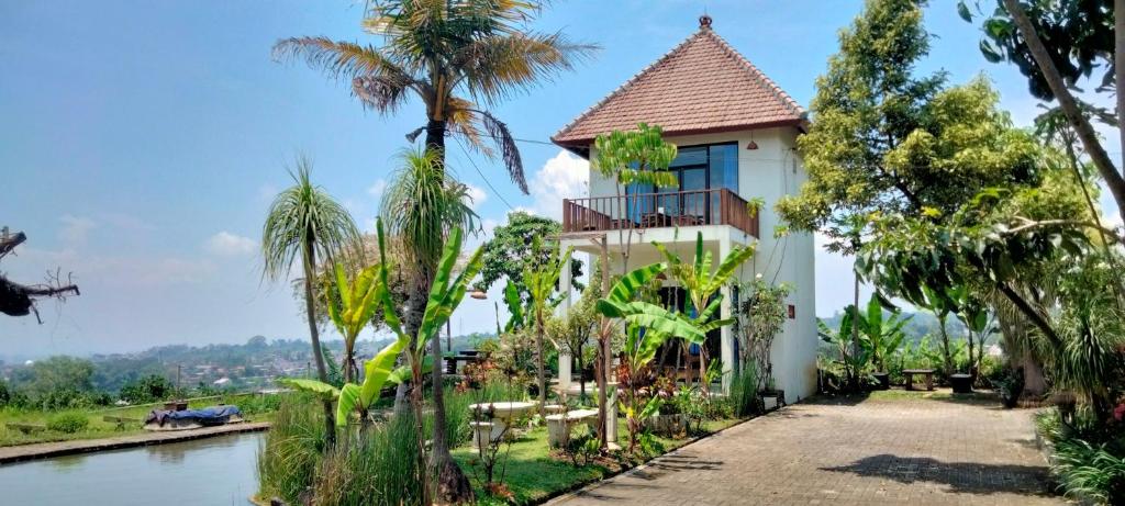 a house with a river and palm trees at Villa Kebun Jeruk Syariah Malang by ecommerceloka in Malang