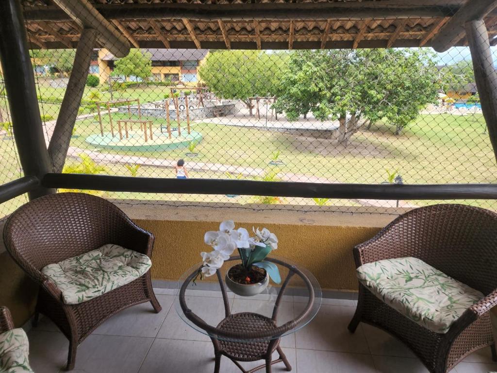 un portico con due sedie e un tavolo con vista su un parco giochi di Lindo e confortável Flat Em Gravatá a Gravatá