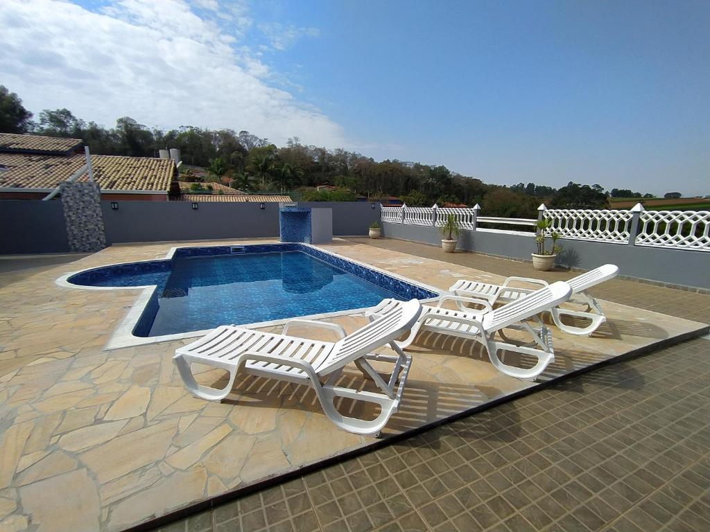 - deux chaises longues et une piscine dans une maison dans l'établissement Chácara Atibaia, à Atibaia