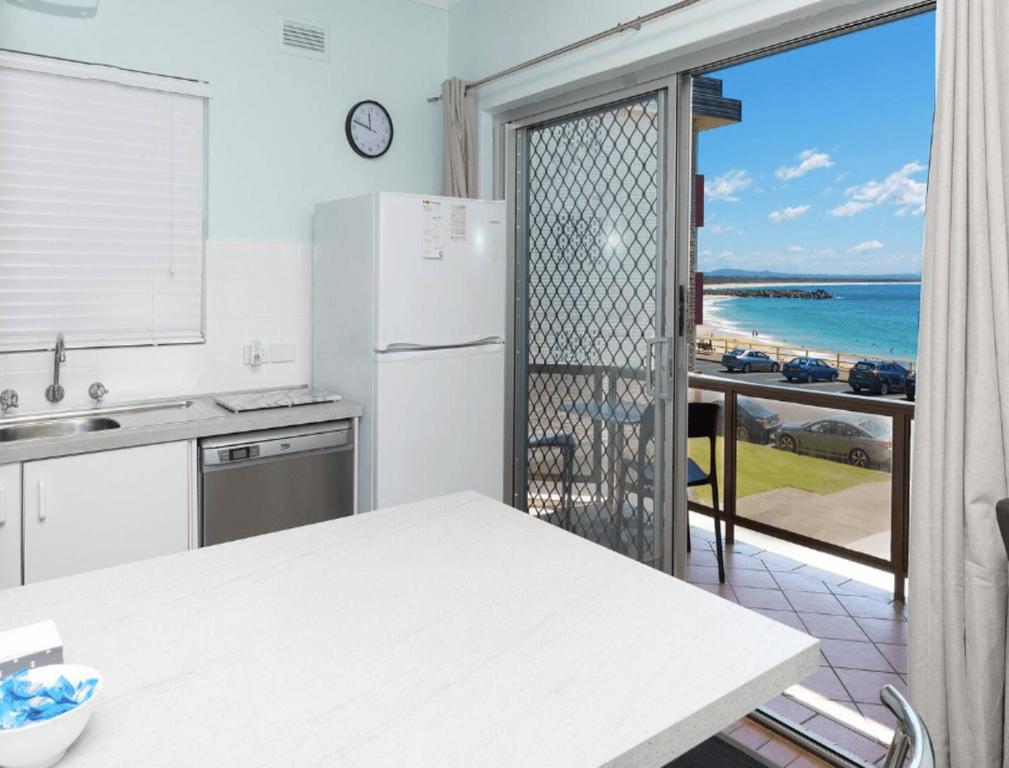 a kitchen with a refrigerator and a view of the ocean at Aloha Beachside in Forster