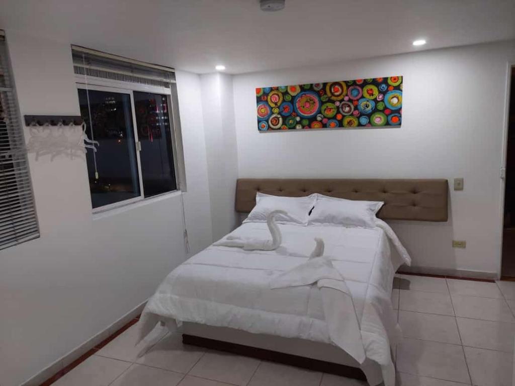 a bedroom with a bed with a painting on the wall at Hotel Bayadera Real in Medellín