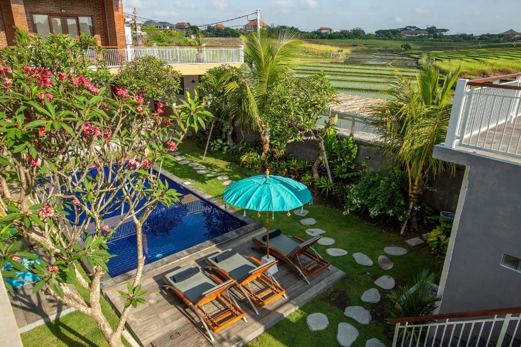 een uitzicht over een zwembad met een parasol en stoelen bij Frangipani House and Spa by ecommerceloka in Canggu