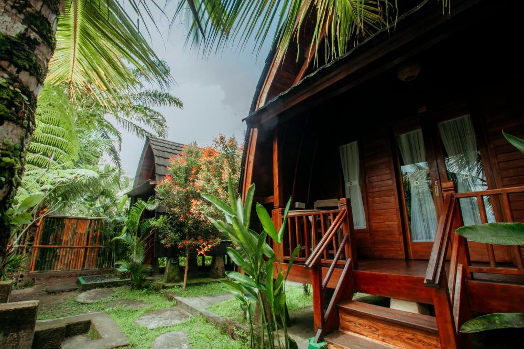 a wooden house with a porch and a palm tree at Ita House in Tegalalang