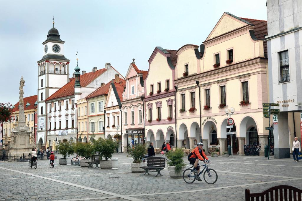 a man riding a bike down a street with buildings at Hotel Zlatá hvězda in Třeboň