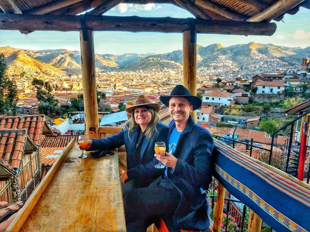 un hombre y una mujer sentados en un balcón con copas de vino en Cities of the World - Apartments Cusco en Cuzco