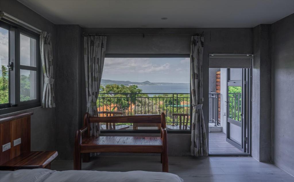 1 dormitorio con vistas al océano desde el balcón en 里夏民宿.墾丁後壁湖 en Hengchun