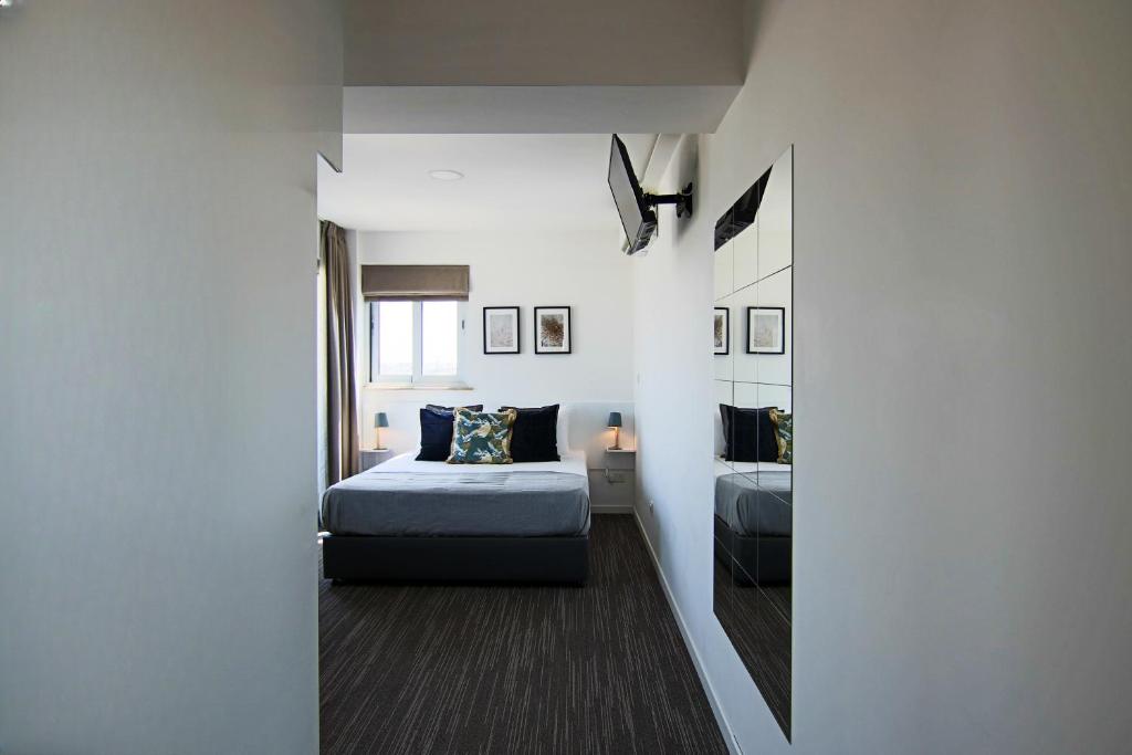 Phaedrus Living: Luxury Suite Nicosia 510 في نيقوسيا: غرفة نوم صغيرة مع سرير ومرآة
