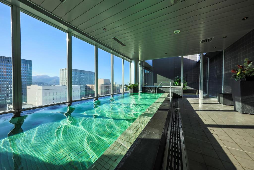 a large swimming pool in a building with windows at Cross Hotel Sapporo in Sapporo