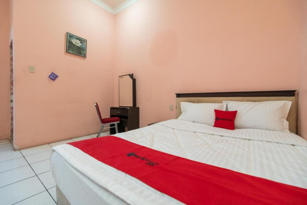 a bedroom with a bed with a red blanket on it at RedDoorz near Silangit International Airport in Siborongborong
