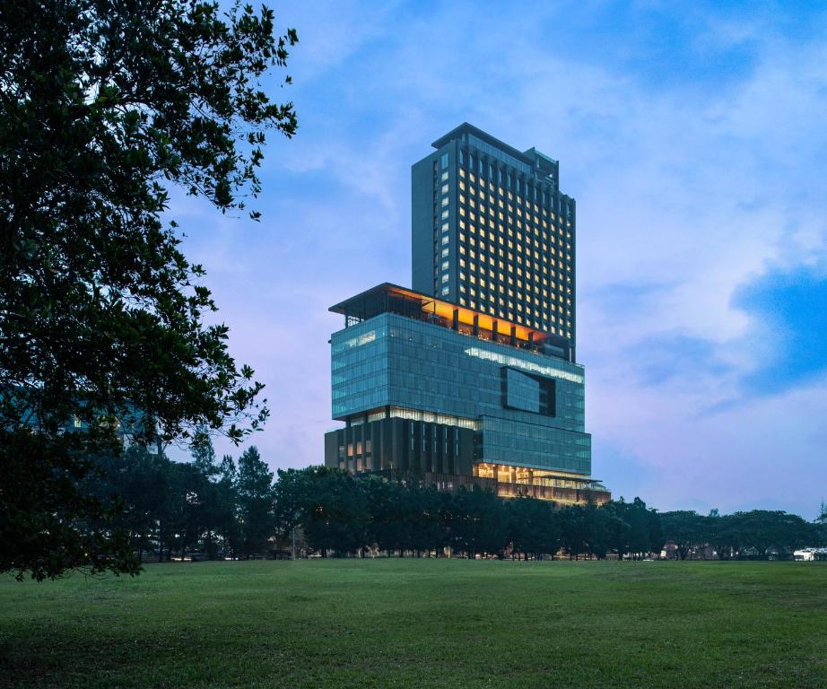 a tall building with its lights on in a park at Trembesi Hotel in Serpong