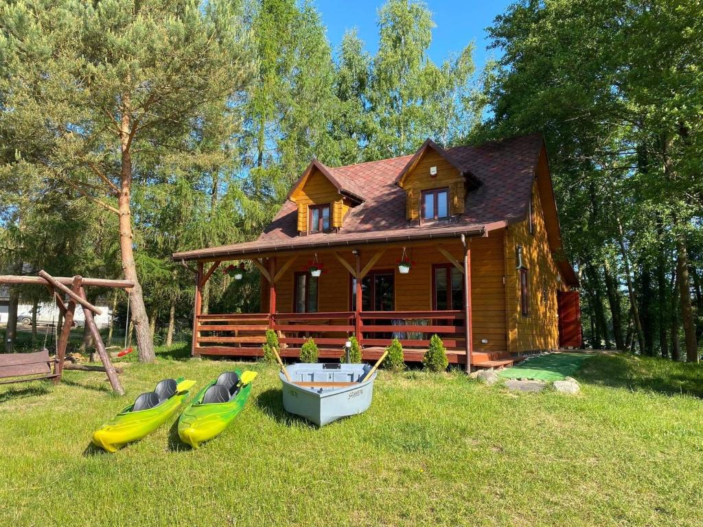 una pequeña casa con barcos en el césped delante de ella en Domek nad jeziorem Winiec, en Miłomłyn