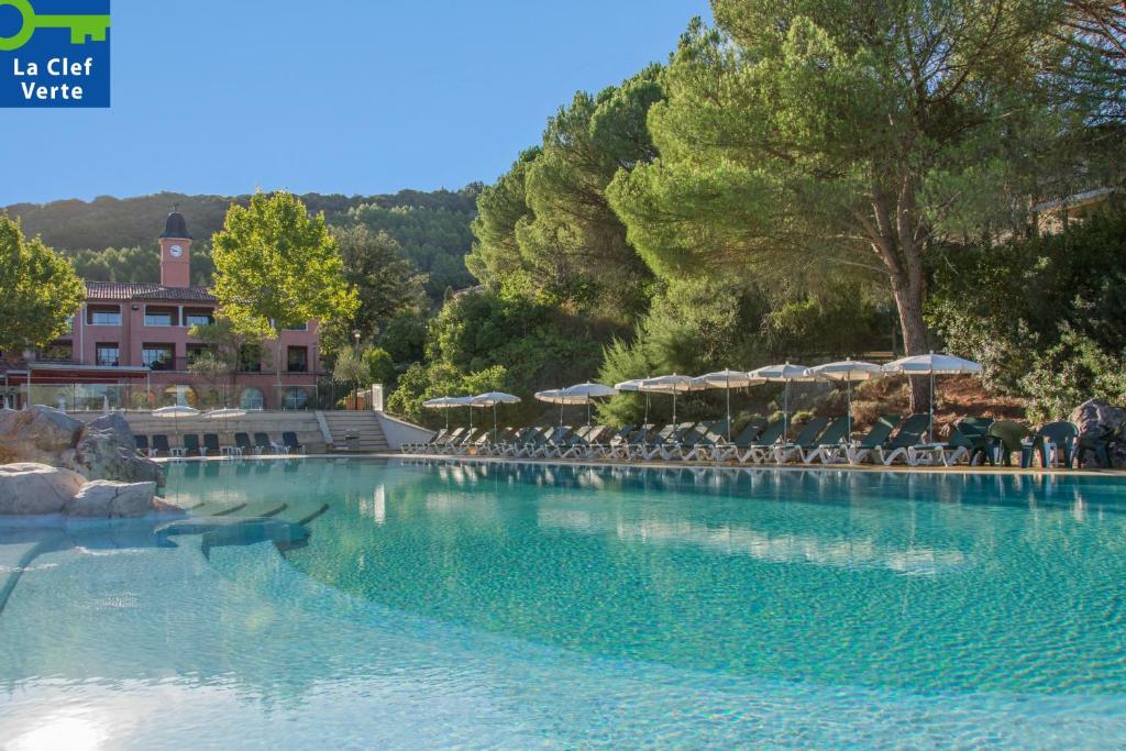 a large pool of water with chairs and umbrellas at Village Pierre & Vacances Le Rouret in Grospierres