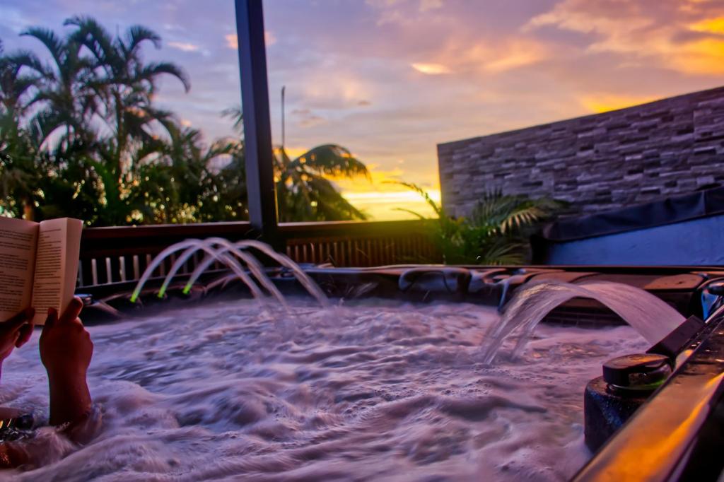 a hot tub in a resort with a sunset at Ka Hema in Saint-Joseph