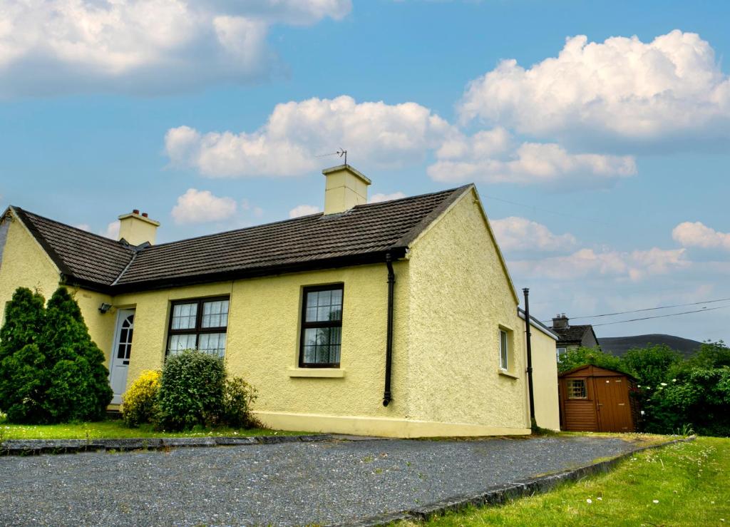 a yellow house on the side of a road at Garden Holiday Cottage by Trident Holiday Homes in Clogheen