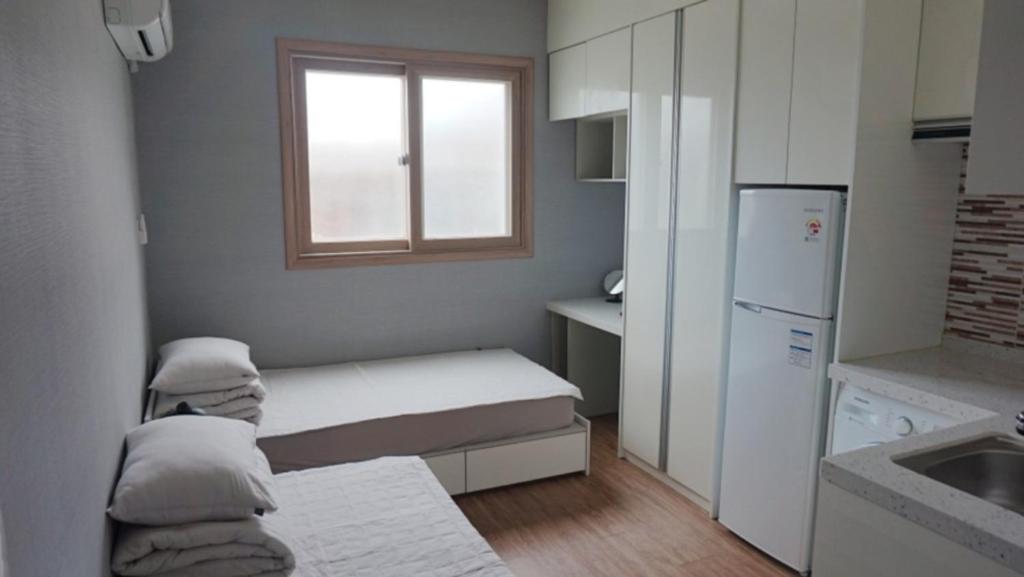 eine kleine Küche mit einem Bett und einem Fenster in der Unterkunft Sh Guesthouse in Chuncheon