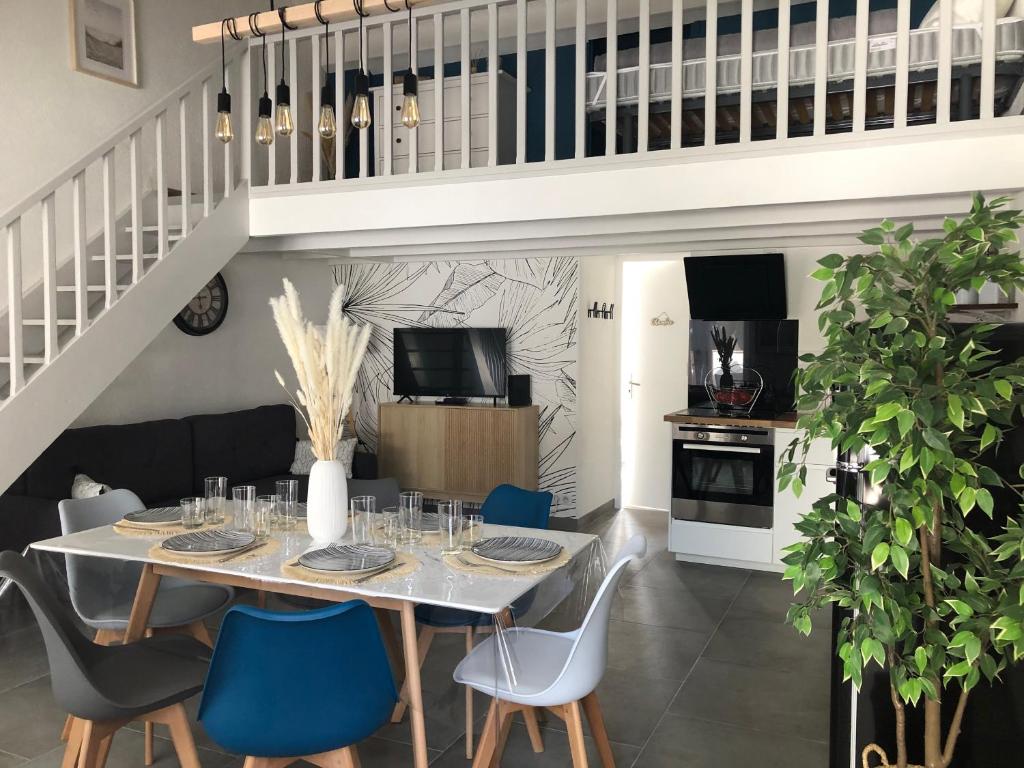 een eetkamer met een tafel en blauwe stoelen bij Maison au cœur de la La Palmyre in Les Mathes