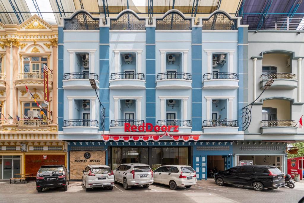 un edificio azul con coches estacionados frente a él en RedDoorz Plus near Ramayana Pematangsiantar, en Pematangsiantar