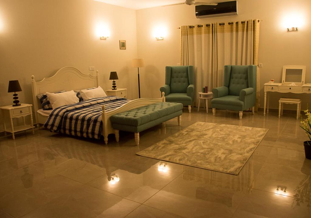 a bedroom with a bed and two chairs and a rug at Hype Holiday Homes in Karachi